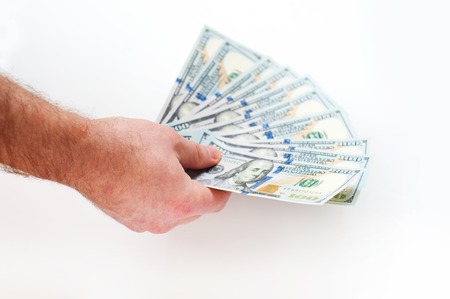 hand of man holding fanned fistful dollars bills.の写真素材