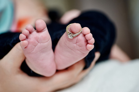 newborn's foot in the mother hand with wedding rings on finger.の写真素材
