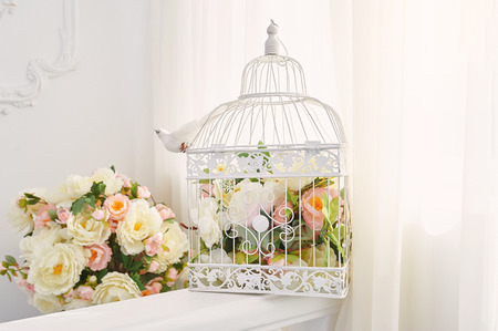 Decorative bird cage with bouquet of flowers in the interior.の写真素材