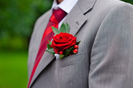 Red boutonniere on gray groom's jacket outdoorの写真素材