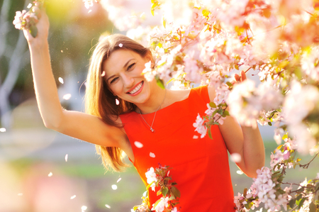 Beautiful Spring woman with blossoming flowers on trees in garden.の写真素材