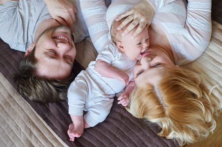 mom and dad playing with his baby son on the bed. Happy family concept.の写真素材