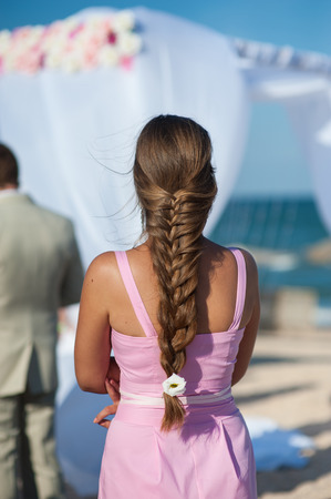 woman with a long braid at the wedding ceremony on beach.の写真素材