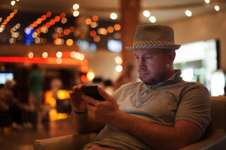 people and technology concept - happy man with smartphone reading message at bar or pub.の写真素材
