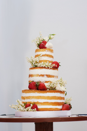 three-tiered wedding cake with strawberries on table.の写真素材