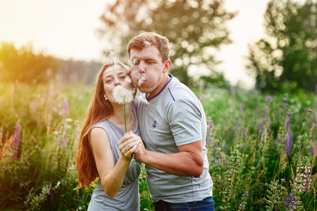 Young happy couple blowing together dandelions, outdoor in nature.の写真素材