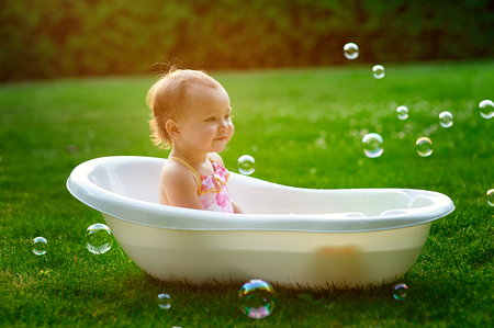 little girl bathes in a bath with soap bubbles.の写真素材