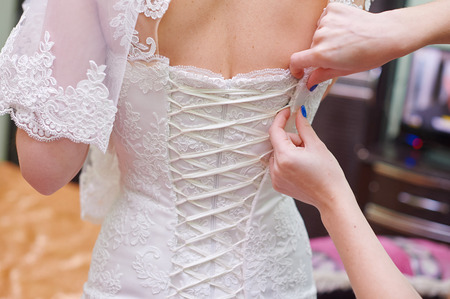 Bridesmaid is helping the bride to dress in morning.の写真素材