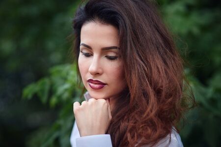Close up portrait of beautiful young happy brunette woman with fresh and clean skin posing in a park