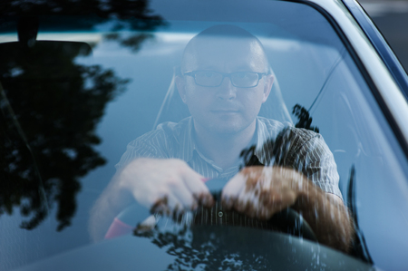 Portrait of young happy businessman with glasses in the carの写真素材