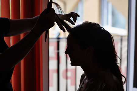 silhouette of Stylist makes make-up bride on the wedding day.の写真素材