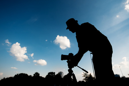 silhouette of a man with a camera on the sky background.の写真素材