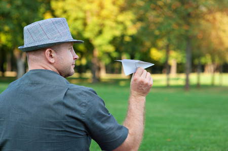 man holding a paper plane in the hand on meadow.の写真素材