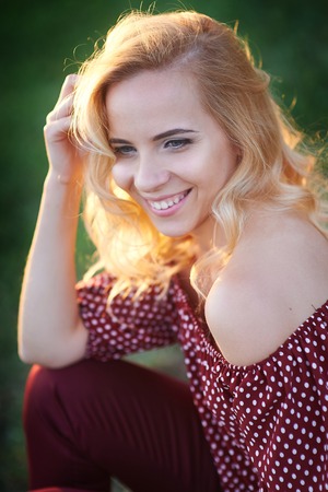 Happy smiling woman in a park on the grass.の写真素材