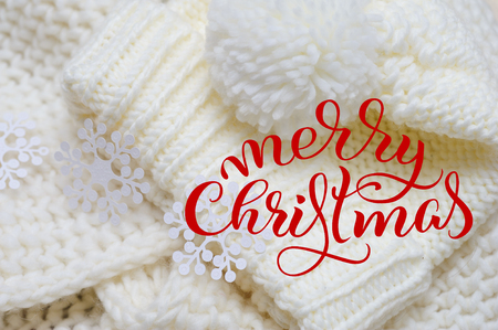 White knit scarf and hat for background with text Merry Christmas. Calligraphy lettering.の写真素材