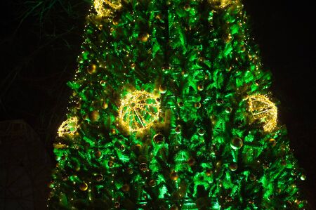 Green Christmas tree with garlands in winter parkの写真素材