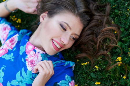 beautiful happy woman lying on the grass with yellow flowers.の写真素材