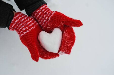 woman in red mittens holding a snowy heartの写真素材