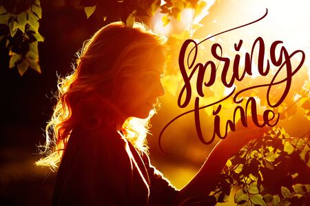 beautiful woman on the background of the setting sun and words Spring time. Calligraphy letteringの写真素材