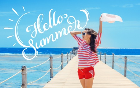happy woman standing on pier with big white hat and text Hello Summer. Calligraphy letteringの写真素材