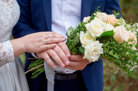 bride put her hand on the bridegroom hand with the wedding bouquetの写真素材