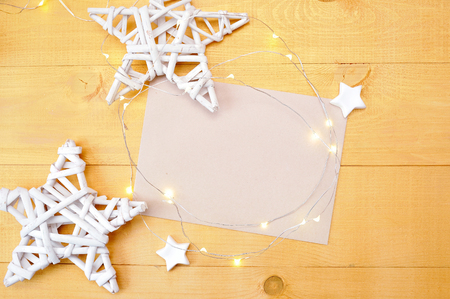 Christmas background kraft sheet of paper with place for your text and white christmas star and garland on a gold wooden background. Flat lay, top view photo mockup.の写真素材