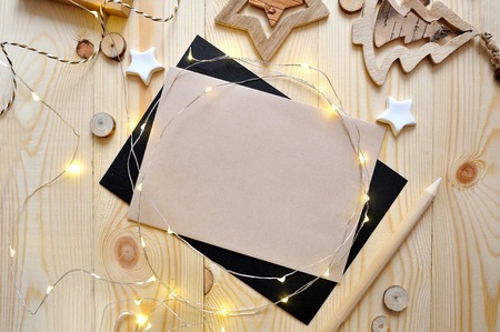 Christmas background kraft sheet of paper with place for your text and white christmas star and garland on wooden background. Flat lay, top view photo mockupの写真素材