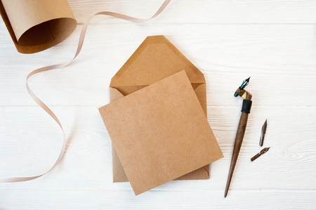 mockup envelope with a letter on a wooden white background with a calligraphic pen. Closeup with clipping pathの写真素材