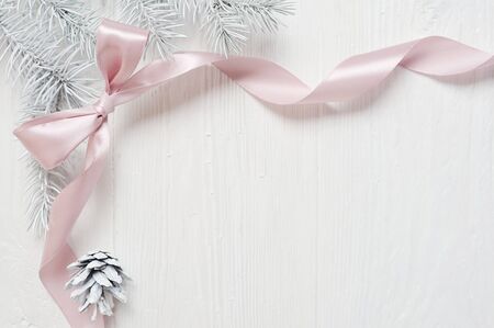 Mockup Christmas tree cone and pink ribbon bow, flatlay on a white wooden background, with place for your textの写真素材