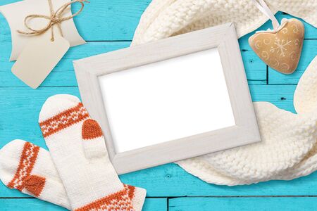 Mockup Christmas white frame with knitted mittens, flatlay on a white wooden background with a ribbon, with place for your text.の写真素材
