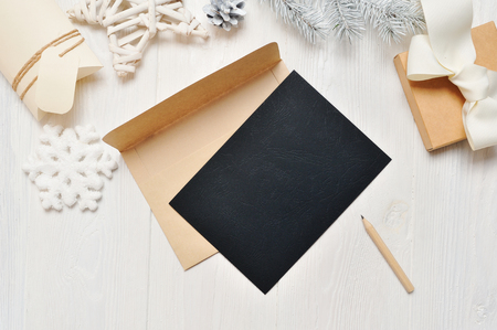 Mockup Christmas black greeting card letter in envelope and pencil, flatlay on a white wooden background, with place for your text, Flat lay, top view photo mock upの写真素材