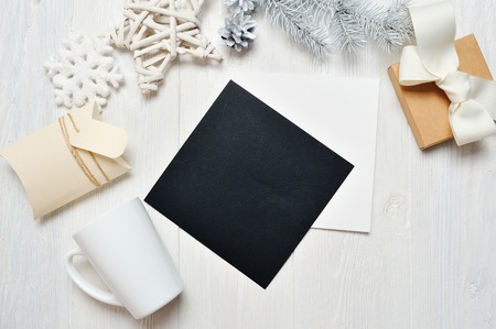 Mockup Christmas black greeting card letter in envelope and mug, flatlay on a white wooden background, with place for your text. Flat lay, top view photo mock upの写真素材