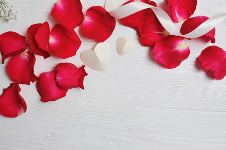 Mockup Rose petals with two white hearts on a white wooden background, card Valentines Day. Flat lay, top view with a place for your text