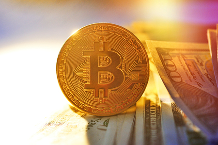 Bitcoin is a gold coin on dollar bills. Financial concept.の写真素材