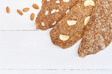 Bread with flaxseeds and almonds on a white wooden background. Useful dietary raw bread vegan breakfast without yeastの写真素材