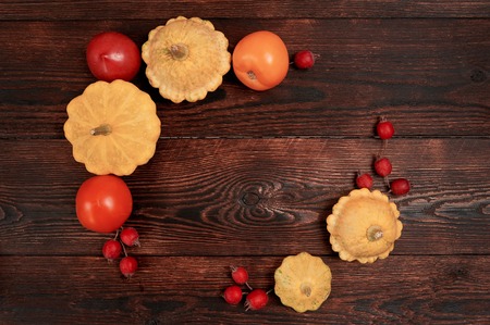 Autumn decor frame with pumpkin and red tomato on dark brown wooden backgound flat lay mockup for your art, picture or hand lettering. Composition copy space, top viewの写真素材