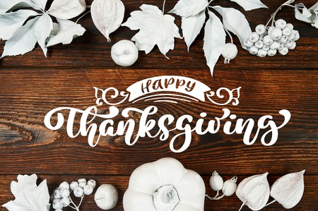 White pumpkin, berries and leaves on a wooden autumn background with text Happy Thanksgiving. Mockup Greeting card for Thanksgiving Day in rustic style . Flat lay. Top viewの写真素材