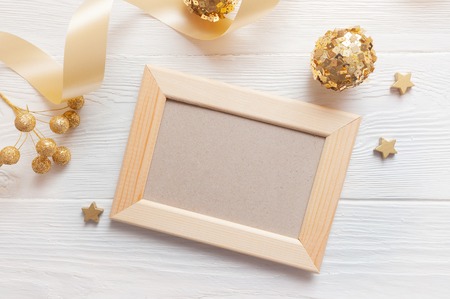 Christmas light wooden frame on a wooden background with ribbon and golden toys. Flat lay, top view...