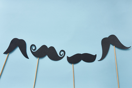 Happy fathers day greeting card with place for text, black mustaches on blue paper background. Hipsters objects flat lay.の写真素材