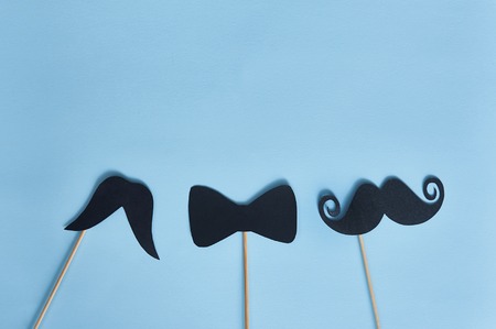 Black mustaches on blue paper background. Happy fathers day greeting card and place for text. Hipsters objects flat lay.の写真素材