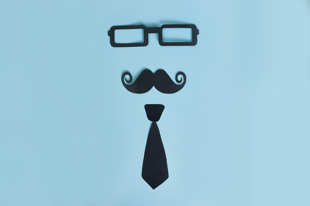 happy father's day flat lay. Decorative man mustache, black glasses and bow-tie on a light blue wooden background. top view greeting card with place for text.の写真素材
