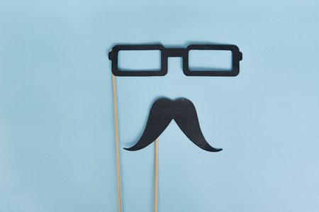 Decorative man mustache and black glasses on a light blue paper background. top view for greeting card with place for text. happy father's day flat lay.の写真素材
