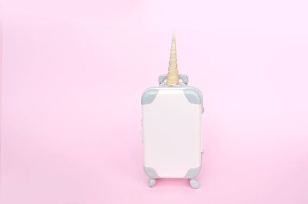 Pink small unicorn suitcase baggage isolated in pink background with place for your text. Concept for travelの写真素材