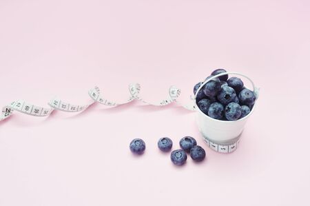 Summer blueberries in bucket on pink background. Berries for design. Close up top view or flat lay...