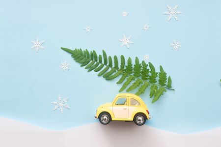 green Christmas tree on yellow toy car with snowflakes. xmas holiday celebration concept. empty copy...