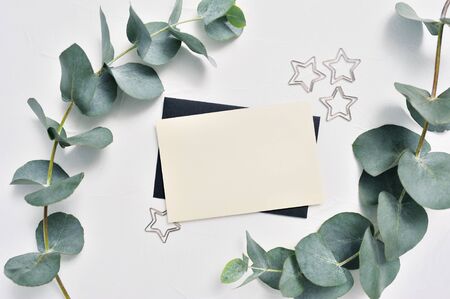Mock up of Eucalyptus leaves and decor of stars paper clip with place for text on white background. Wreath made of eucalyptus branches. Flat lay, top viewの写真素材