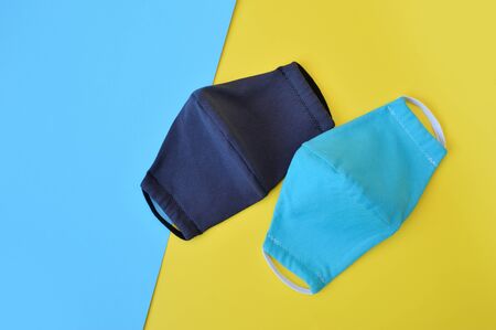 Protective two tourquise and dark gray face virus masks on blue and yellow background. Coronavirus Protectionの写真素材