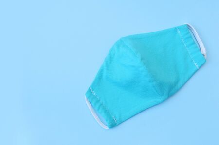 Protective turquoise face virus mask nurse on blue paper background with place for your text....