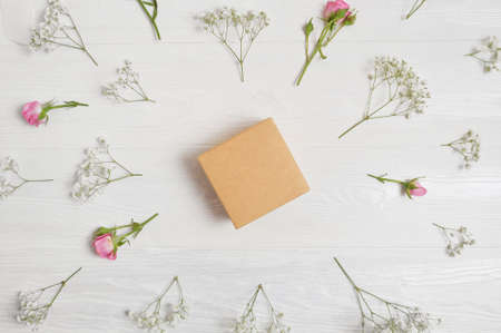 Craft spring gift box in center and flowers arroud gift box. Greeting card for Valentines Day with place for your text. Flat lay, top view photo mock upの写真素材