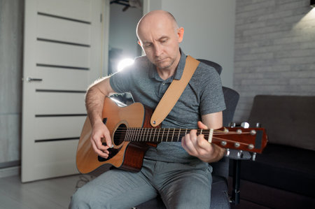 Guitarist paying a acoustic guitar in office. portrait Male musician sitting on sofa and playing...